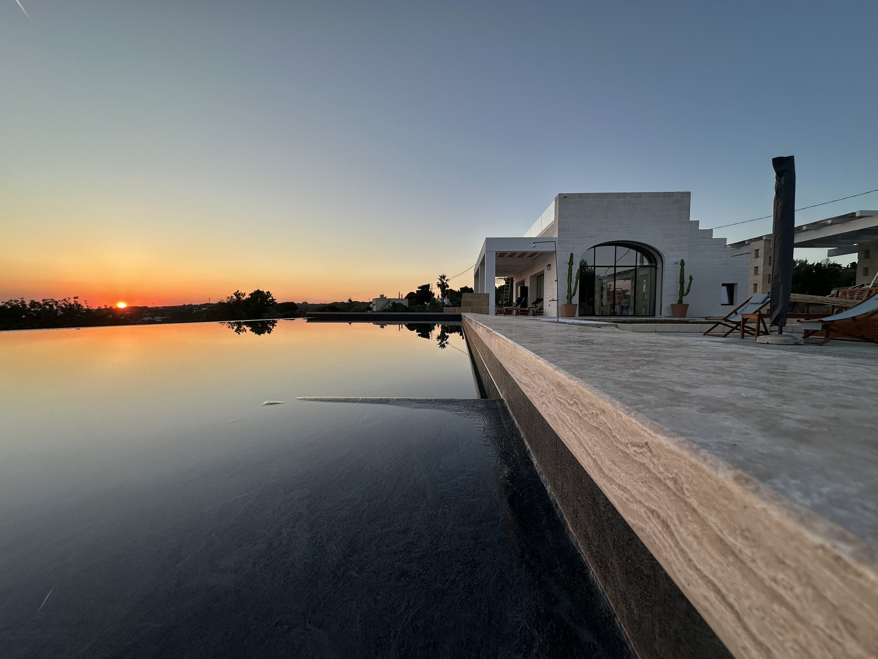 Villa et piscine à débordement au coucher du soleil
